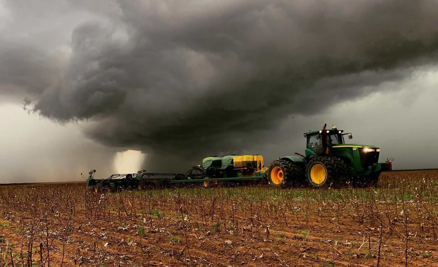 trator plantando com chuva ao fundo